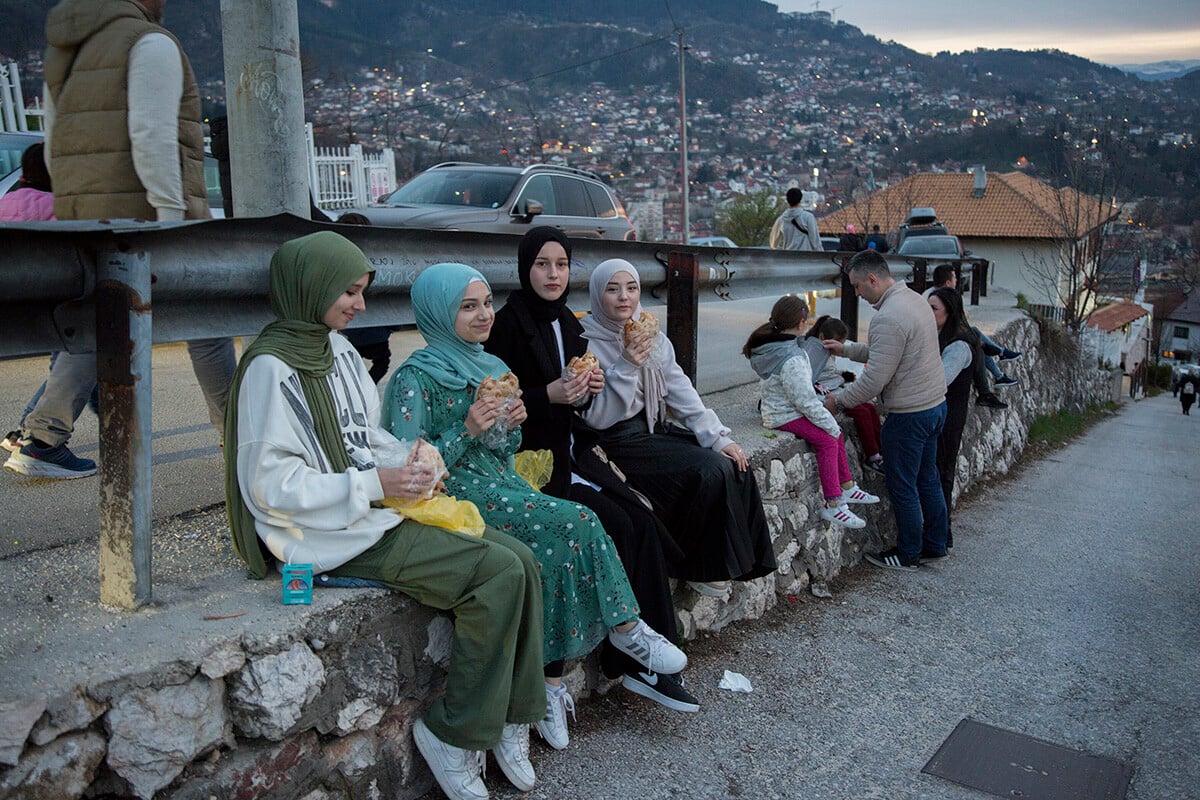 Veriace dievčatá sedia popri ceste neďaleko Žltej bašty, kde prerušili pôst. Viacerí ľudia postávajú tiež neďaleko a jedia, čo si so sebou priniesli. Foto: Zuzana Gogová