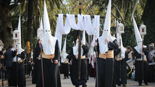 Biele kukly a kajúcnici nesúci trojtonový trón. Semana Santa je sviatok, ktorý cítiť v kostiach